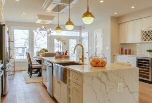 A beautiful light colored themed kitchen with shelves, cabinets and workstation